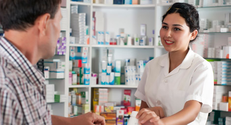 A male pharmacist stood with his arms crossed in front of medication shelves